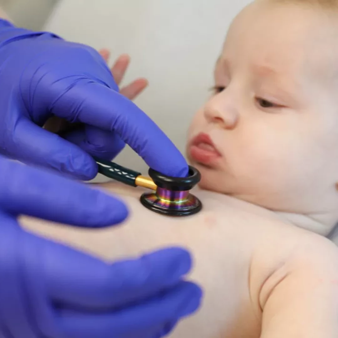 Baby being examined with a stethoscope by a healthcare provider wearing blue gloves at Highland Health Providers.